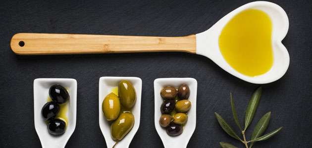 Presentación de olivas en una mesa con una cuchara de aceite